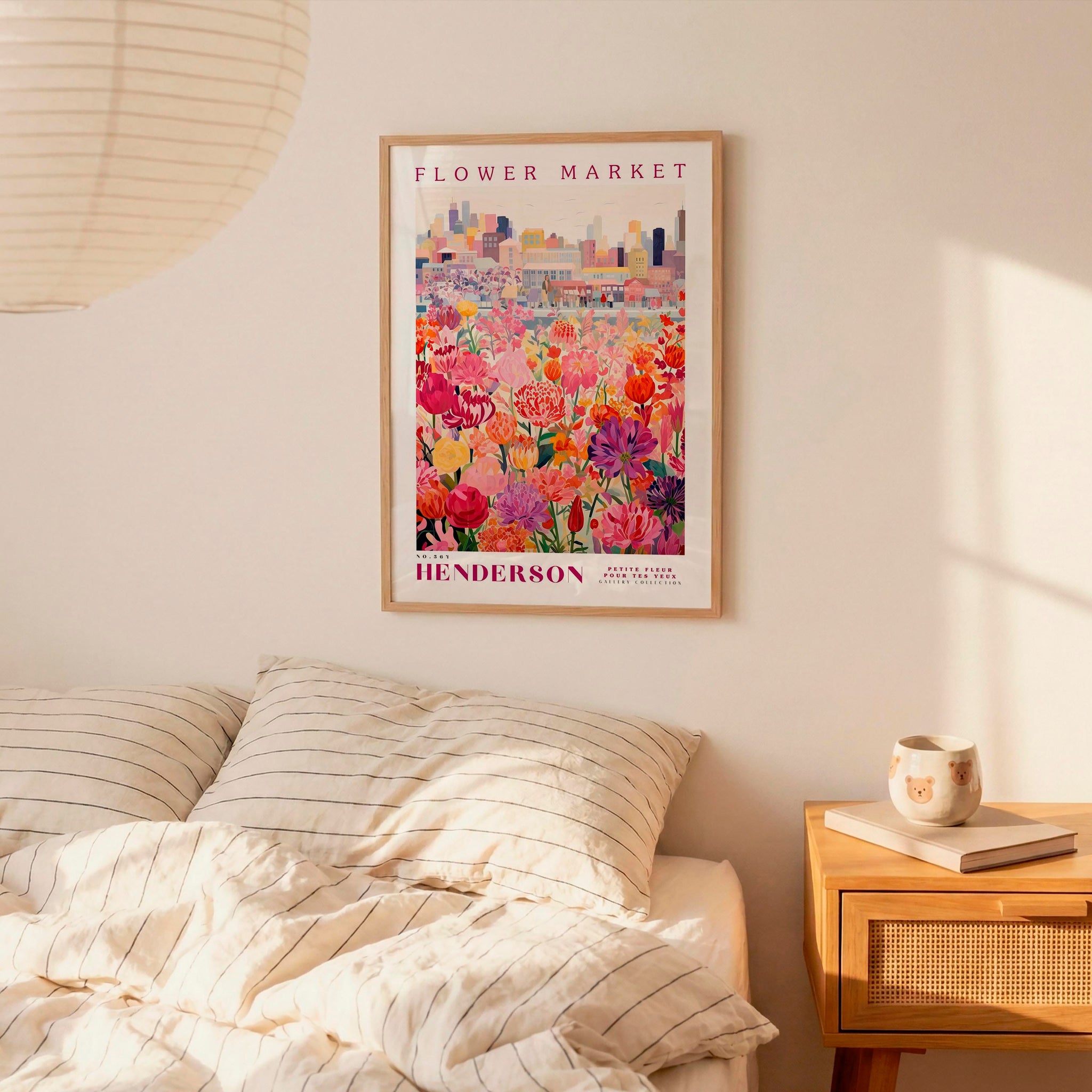 a bedroom setting with a framed poster of a colorful flower market hanging on the wall above a bed with striped pillows.