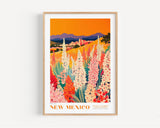 The image is a framed poster depicting a vibrant landscape with a field of colorful flowers, mountains in the background, and a warm orange sky.