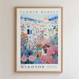 The image is a framed poster depicting a colorful and vibrant flower market in a city, with buildings, flowers, and greenery surrounding the scene.