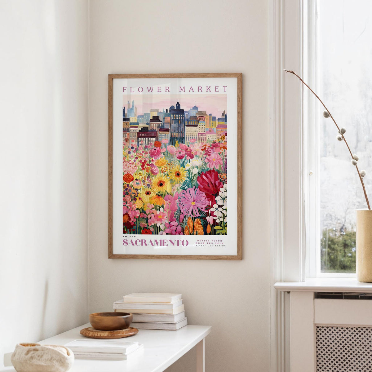 a framed poster of a colorful cityscape with a flower market in the background, hanging on a wall in a room.