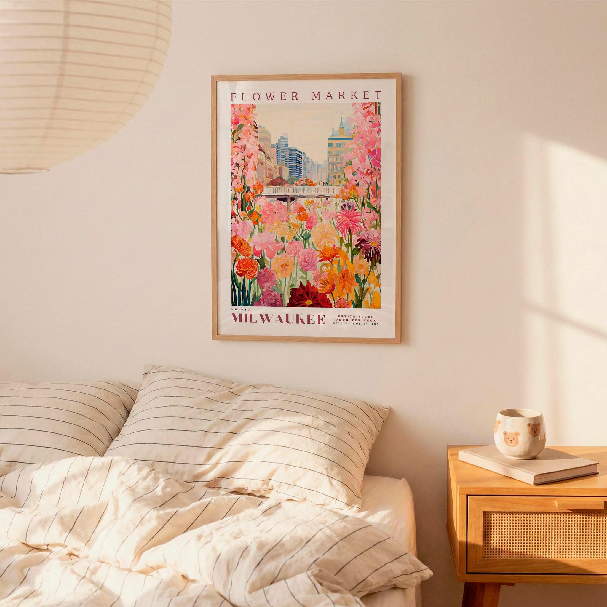 a bedroom setting with a framed poster of a colorful floral scene hanging on the wall above a bed with striped pillows.