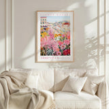 a poster of a flower market in the city of Asheville, North Carolina, hanging on a wall above a white couch.