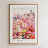 The image is a framed poster depicting a vibrant and colorful flower market in MESA, with a variety of flowers and buildings in the background.