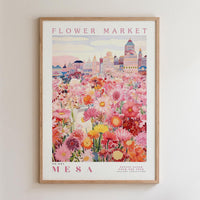 The image is a framed poster depicting a vibrant and colorful flower market in MESA, with a variety of flowers and buildings in the background.
