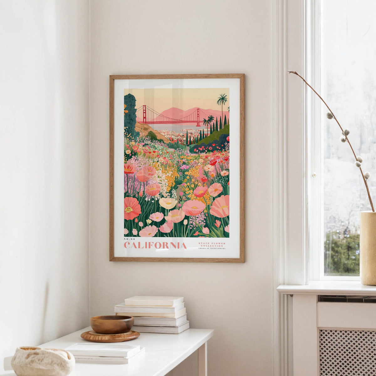 a framed poster of a colorful garden scene with flowers and a bridge in the background, hanging on a wall in a room.