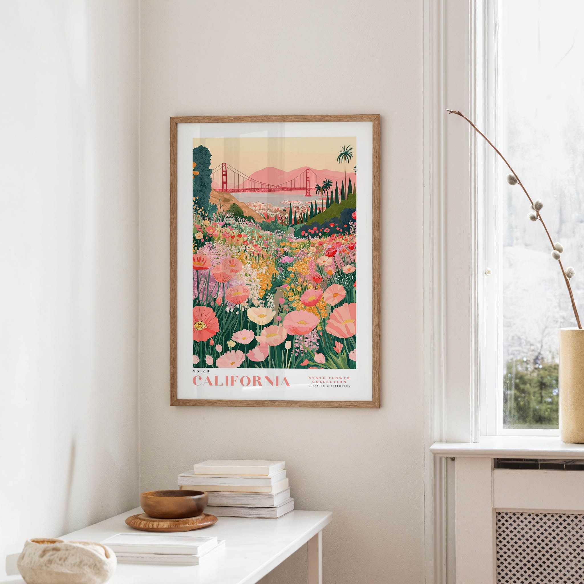 a framed poster of a colorful garden scene with flowers and a bridge in the background, hanging on a wall in a room.