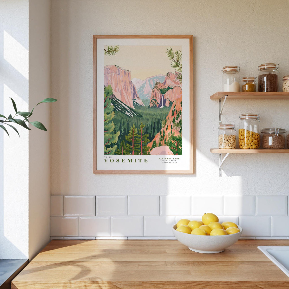 a kitchen counter with a bowl of lemons, a framed poster of Yosemite National Park, and a shelf with jars and bottles.