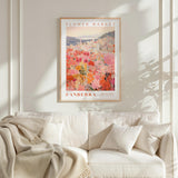 a framed poster of a flower market in Australia hanging on a wall above a white couch with a blanket draped over it.