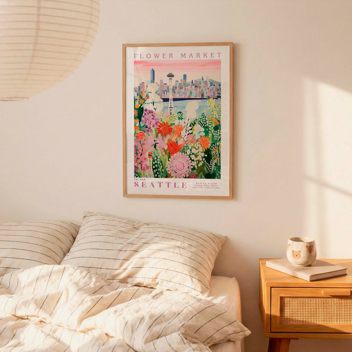 a bedroom with a framed poster of a cityscape hanging on the wall above a bed with striped pillows.