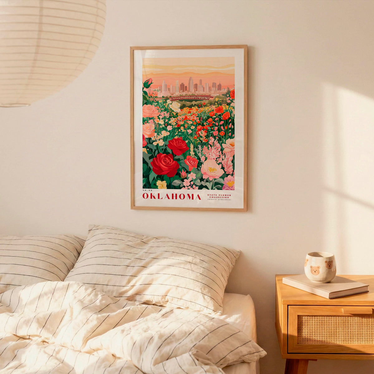 a bedroom scene with a framed poster of a flower garden hanging on the wall above a bed with striped pillows.