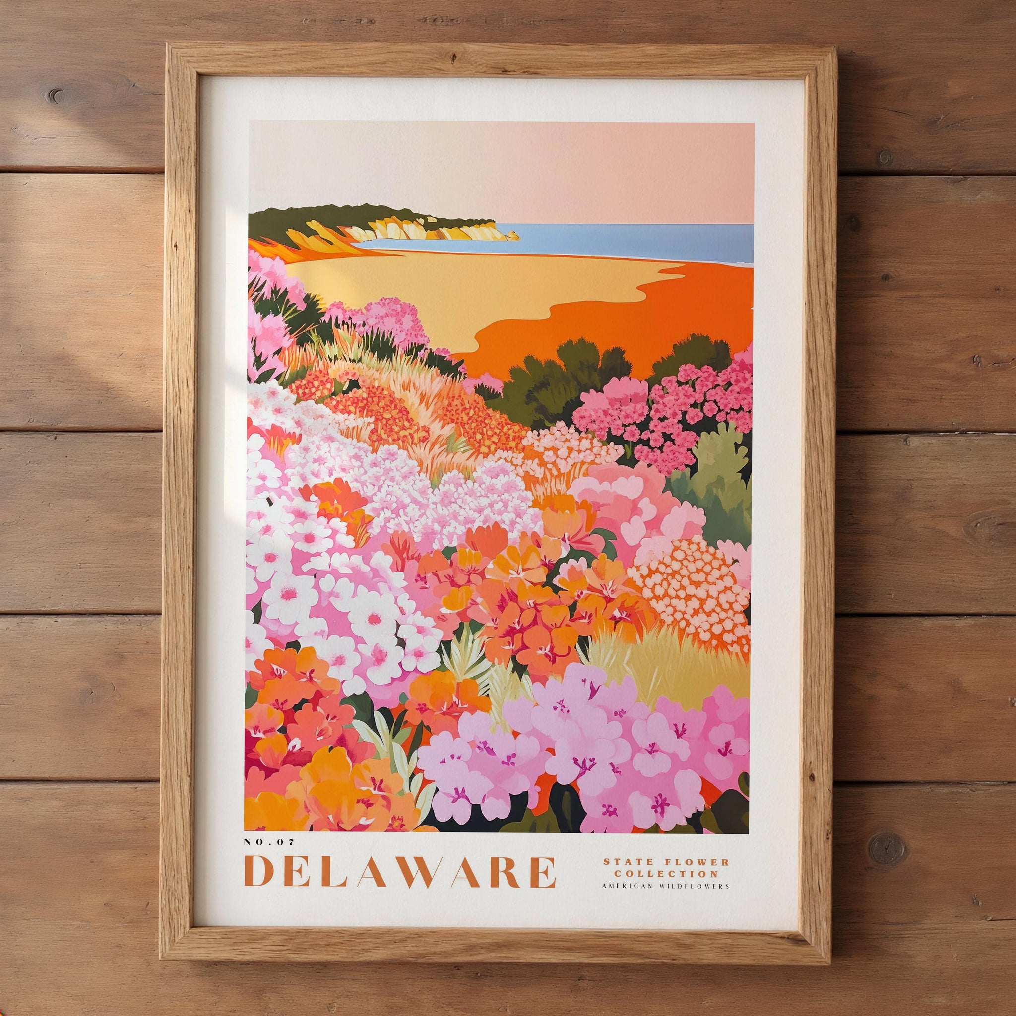 A framed poster depicting a vibrant field of flowers, with a coastal landscape in the background.