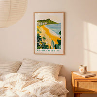 a bedroom with a framed poster of a beach scene hanging on the wall above a bed with striped pillows.