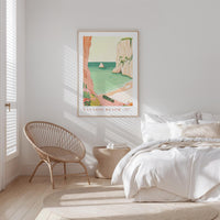 a serene bedroom scene with a large bed, a woven chair, and a framed poster of a beach landscape hanging on the wall.