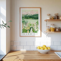 a framed poster of a scenic landscape with mountains and a lake, hanging on a wall above a wooden countertop with a bowl of lemons.