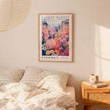 a bedroom scene with a framed poster of a colorful garden hanging on the wall above a bed with striped pillows.