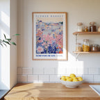 a kitchen scene with a framed poster of a colorful floral scene hanging on the wall above a wooden countertop with a bowl of lemons.