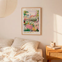 a bedroom setting with a framed poster of a flower market hanging on the wall above a bed with striped pillows.