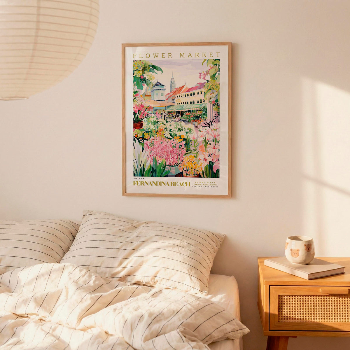 a bedroom setting with a framed poster of a flower market hanging on the wall above a bed with striped pillows.