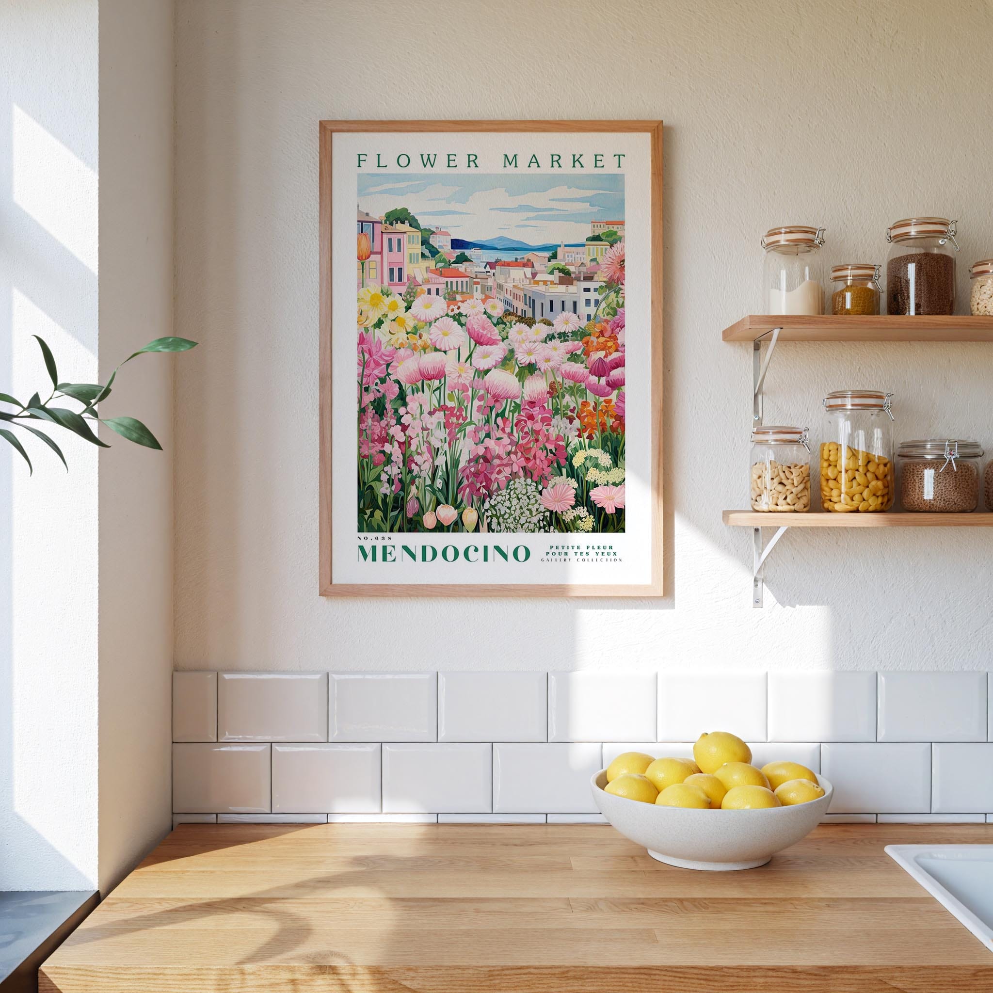 a framed poster of a flower market in Mendocino, California, hanging on a wall above a kitchen counter with a bowl of lemons.