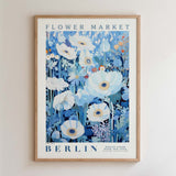 The image is a framed poster depicting a vibrant floral scene with white and blue flowers, including daisies and peonies, against a blue background.