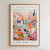 The image is a framed poster depicting a cityscape with a river and colorful flowers in the foreground.
