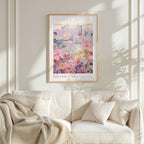 a framed poster of a cityscape with flowers, hanging on a wall above a white couch with pillows.