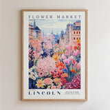 A framed poster depicting a vibrant and colorful flower market in Lincoln, with a variety of flowers and buildings in the background.