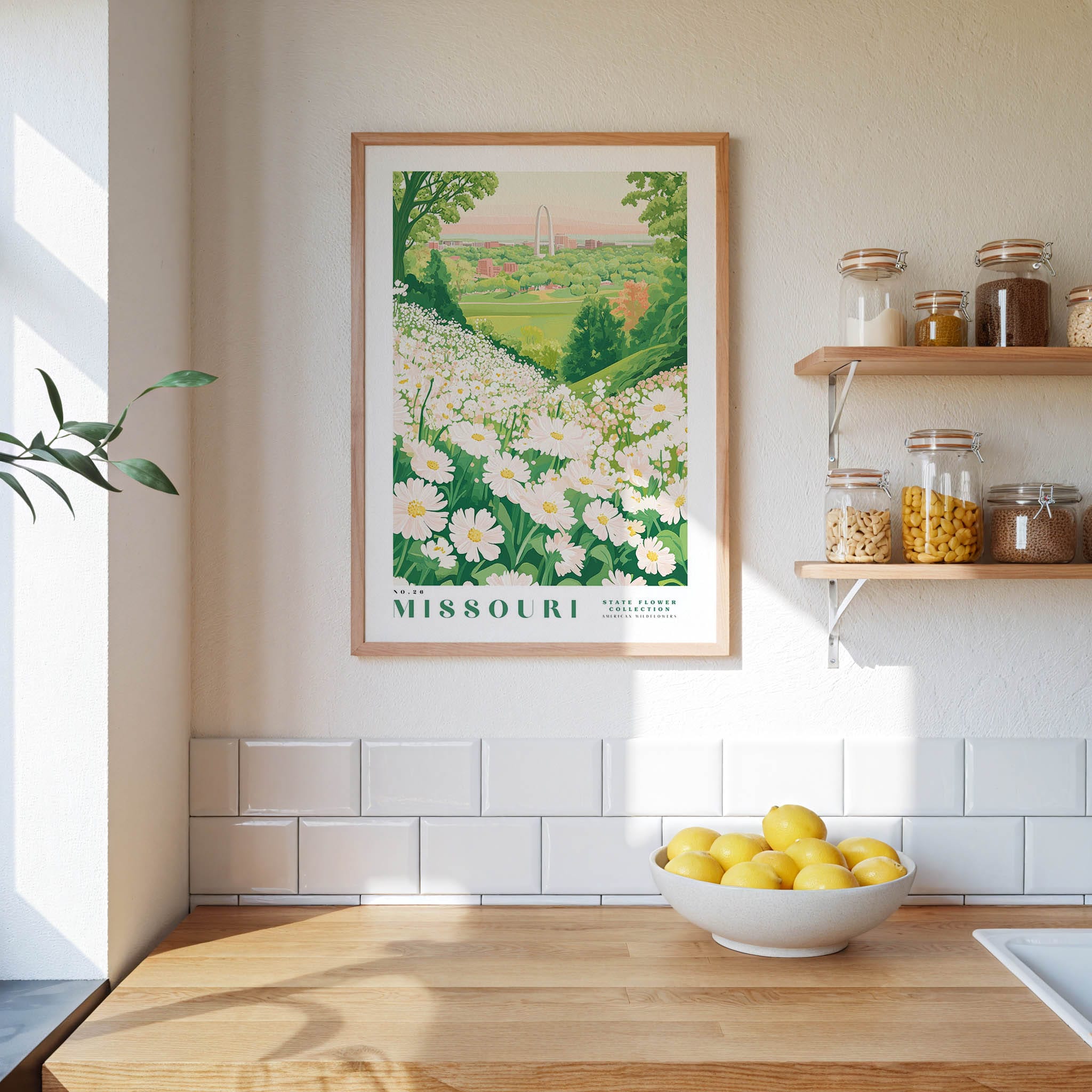 a framed poster of a field of white flowers hanging on a wall above a wooden countertop with a bowl of lemons.