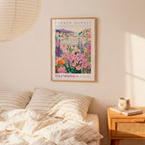 a bedroom scene with a framed poster of a colorful floral scene hanging on the wall above a bed with striped pillows.
