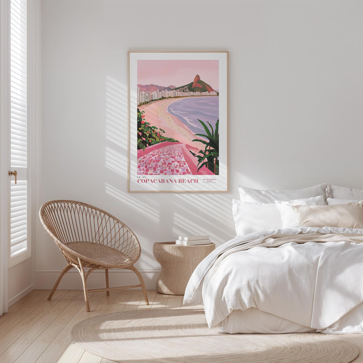 a bedroom with a large framed poster of Copacabana Beach hanging on the wall, a wicker chair, and a white bed with a beige blanket.