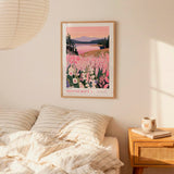 a bedroom scene with a framed poster of a scenic landscape hanging on the wall above a bed with striped pillows.