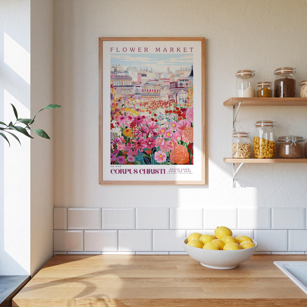 a kitchen scene with a framed poster of a colorful flower market hanging on the wall above a wooden counter. On the counter, there is a bowl of lemons and a plant.