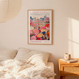 a bedroom scene with a framed poster of a cityscape and a bed with striped pillows.