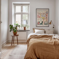 a cozy bedroom with a large bed, a wooden nightstand, and a window with a plant on the sill. The room has a warm, inviting atmosphere with a neutral color palette and natural elements like the potted plant and the rug.