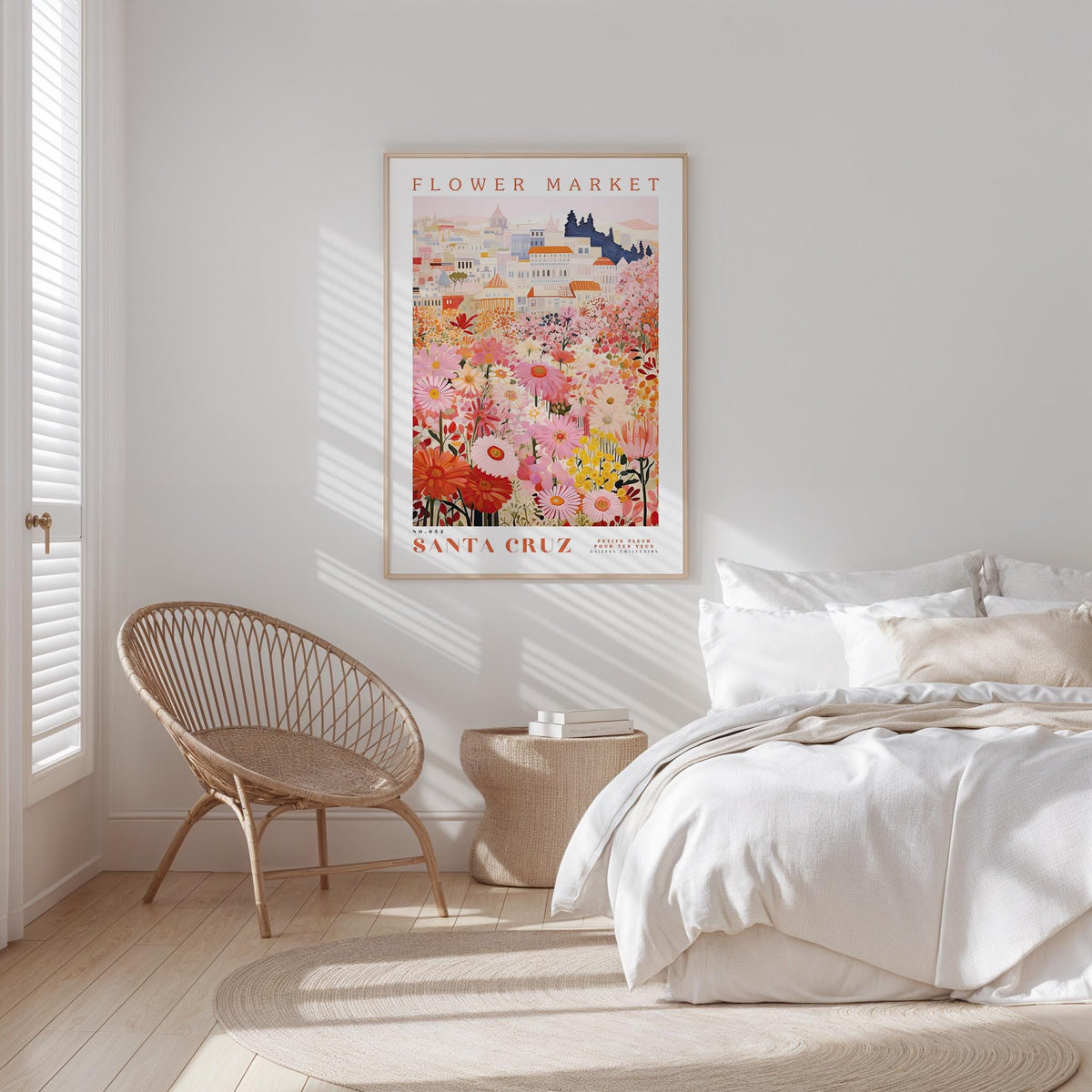 a bedroom with a bed, a woven chair, and a framed poster of a colorful floral scene hanging on the wall.