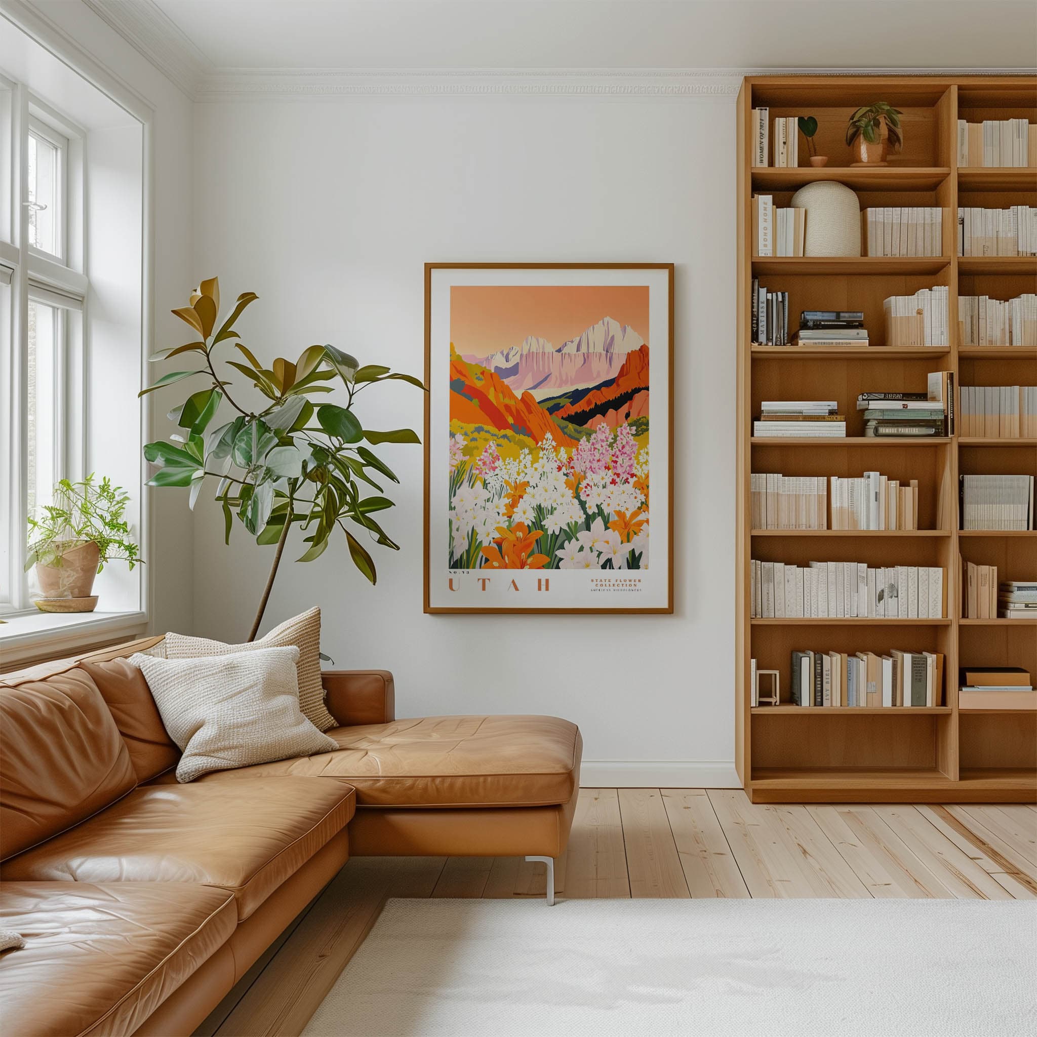 a cozy living room with a large window, a comfortable leather sofa, a wooden bookshelf filled with books, and a framed poster of a mountain landscape hanging on the wall.