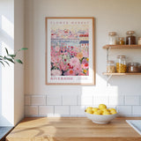 a kitchen scene with a framed poster of a flower market on the wall, a wooden counter with a bowl of lemons, and shelves displaying various jars and containers.