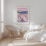 A bedroom with a large poster of a scenic view of Rhode Island hanging on the wall, featuring a colorful landscape with boats and flowers. The room has a white bed, a woven chair, and a small side table.