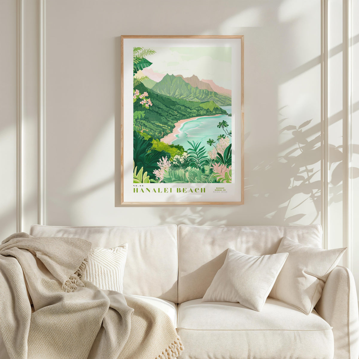 a framed poster of a tropical beach landscape hanging on a wall above a white couch with a blanket draped over it.