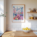 a framed poster of a colorful illustration of a flower market in Madrid, Spain, hanging on a wall above a wooden counter with a bowl of lemons.