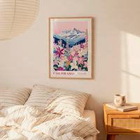 a bedroom scene with a framed poster of a mountain landscape hanging on the wall above a bed with striped pillows.
