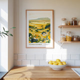 a kitchen counter with a bowl of lemons, a framed print of a landscape, and shelves with jars and containers.