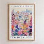The image is a framed poster depicting a vibrant and colorful cityscape with a variety of flowers and plants in the foreground.