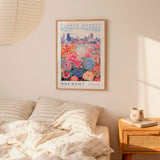 a bedroom scene with a framed poster of a flower market hanging on the wall above a bed with striped pillows.