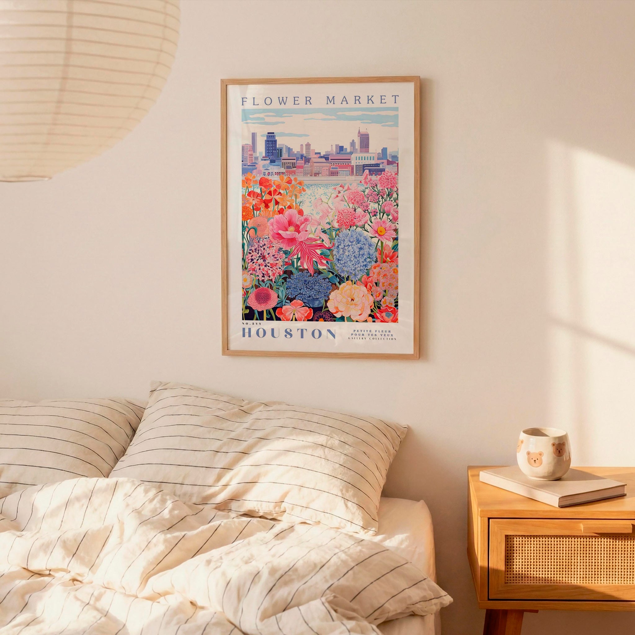 a bedroom scene with a framed poster of a flower market hanging on the wall above a bed with striped pillows.