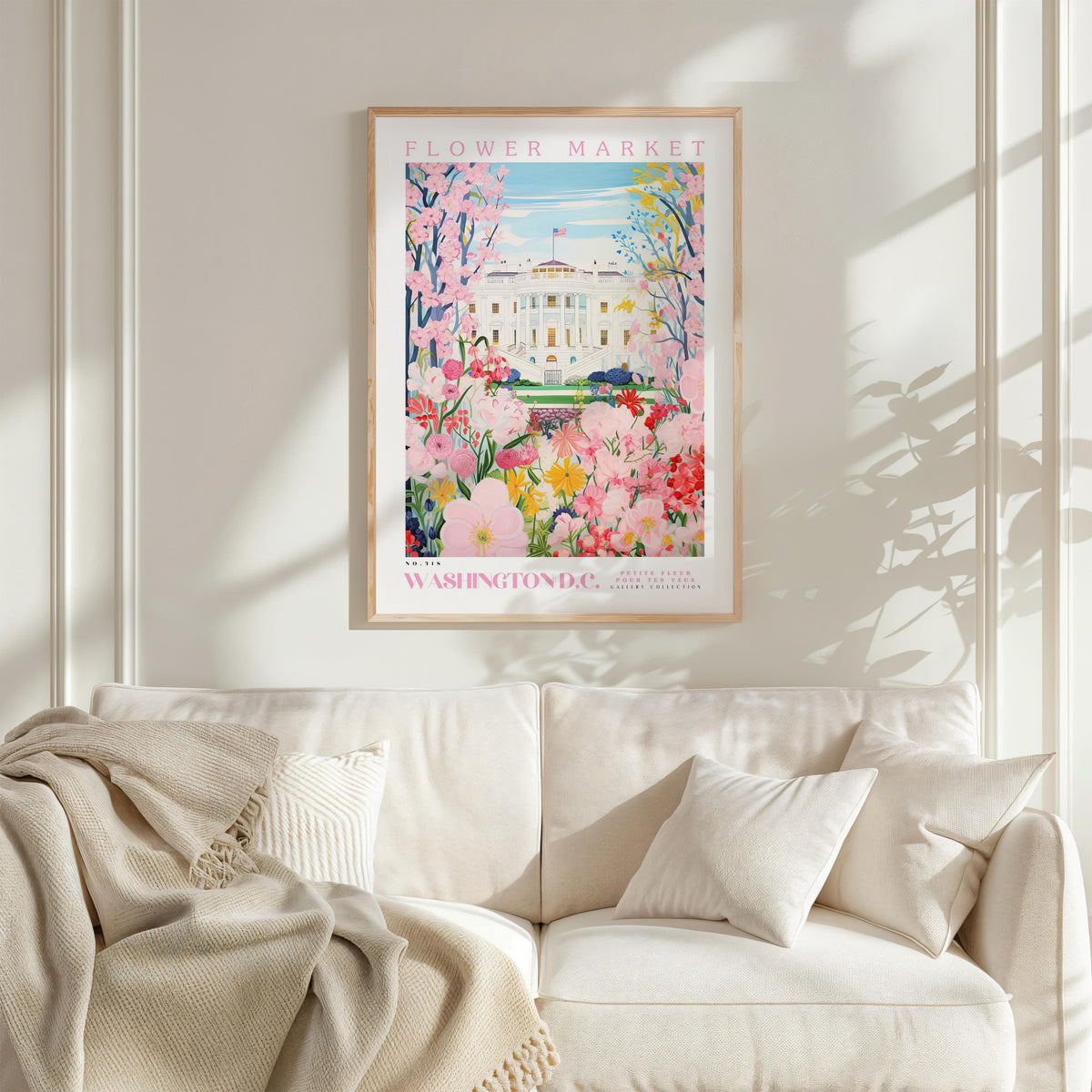 a framed poster of the Washington Monument, a famous landmark in Washington, D.C., with a vibrant floral scene surrounding it. The poster is hung on a wall above a white couch, creating a cozy and inviting atmosphere in the room.