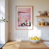 a kitchen scene with a framed poster of a flowery landscape hanging on the wall, a bowl of lemons on the counter, and shelves displaying various jars and containers.