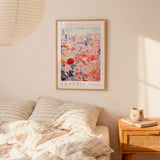 a bedroom scene with a framed poster of a cityscape and a bed with striped pillows.