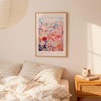a bedroom scene with a framed poster of a cityscape and a bed with striped pillows.
