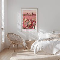 A bedroom with a large bed, a woven chair, and a framed poster of a cityscape with flowers on the wall.